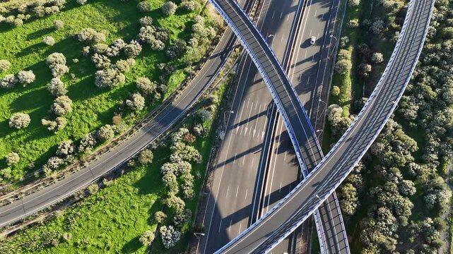 Top-down aerial view of a highway interchange with multiple roads and cars in motion.