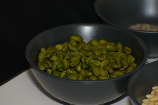 Shelled Green Pistachio Kernels in Black Ceramic Bowl
