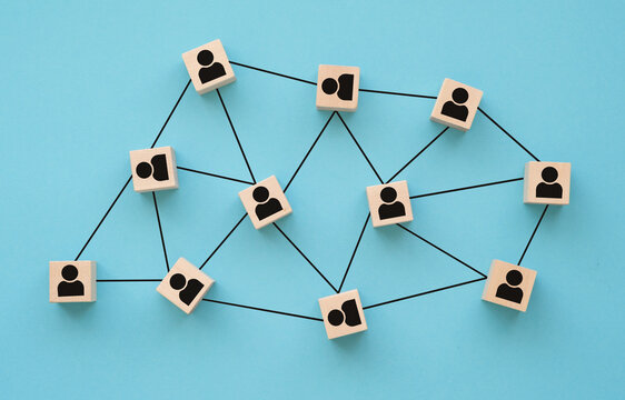 Organizational network structure with connected people icons on wooden blocks, showing team collaboration, stakeholder mapping, social graph. Business concept