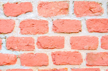 Obraz premium A close-up of a fragment of old brickwork. The wall is made of red brick. Defects and cracks in the brick wall.
