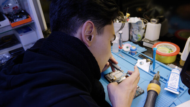 Technician repairing smartphone at service center desk