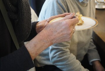 Oberk&ouml;rper von alter schlanker Frau mit schwarzem Wollpullover mit Muster beim Kuchen essen auf Fest in Raum