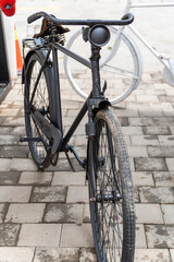 Obraz premium Vintage black bicycle parked on paved street. Classic old style bike with worn tires and retro design
