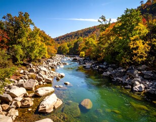 A vibrant autumn landscape showcases a clear, flowing river weaving through a valley filled with colorful foliage under a bright blue sky