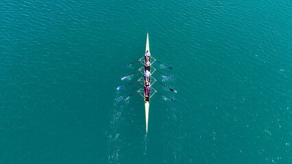 Aerial drone top down photo of team of Athletes rowing in sport canoe in emerald deep blue sea © aerial-drone