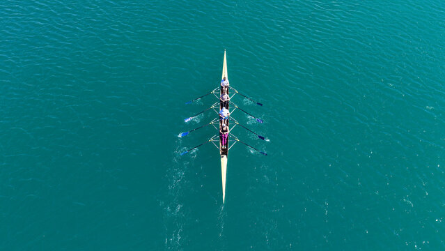 Aerial drone top down photo of team of Athletes rowing in sport canoe in emerald deep blue sea
