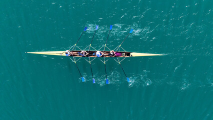 Aerial drone top down photo of team of Athletes rowing in sport canoe in emerald deep blue sea © aerial-drone