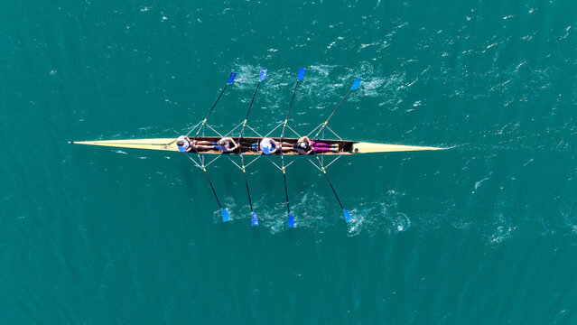 Aerial drone top down photo of team of Athletes rowing in sport canoe in emerald deep blue sea