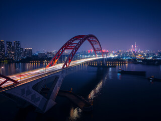 Obraz premium Night aerial view of Guangzhou with illuminated bridge and city skyline, concept highway car jam of China