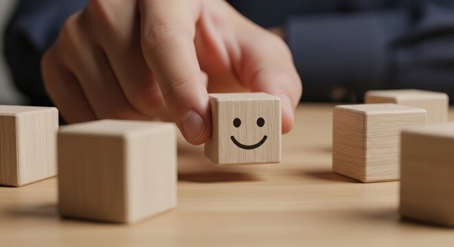 Hand holding a wooden block with a smiley face among other blocks on a table in a closeup view  concept of positive feedback or good customer service