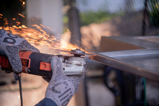 El hombre est&aacute; cortando una hoja de metal con una amoladora.
