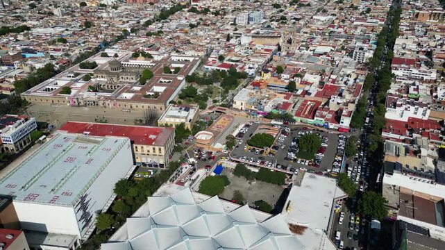 Drone footage of Guadalajara, Mexico, showing San Juan de Dios Market, Cabanas Cultural Institute, and Cabanas Garden amidst city buildings.
