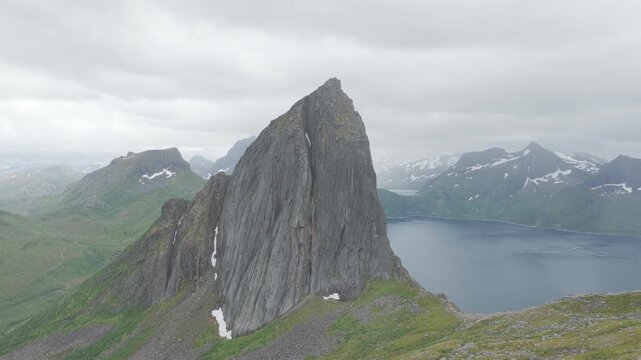 Aerial, forward drone flight, impressive peak and cliff of famous Segla on Senja island during cloudy summer day. Some rain, Amazing hiking destination, outdoor adventure. Fjords and mountains.