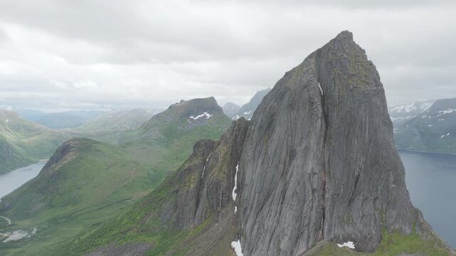 Aerial, forward drone flight, impressive peak and cliff of famous Segla on Senja island during cloudy summer day. Some rain, Amazing hiking destination, outdoor adventure. Fjords and mountains.