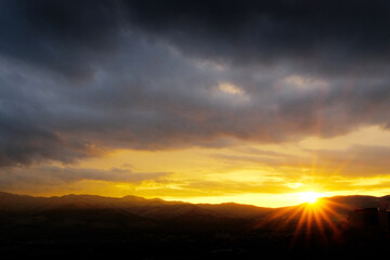 Sunstar at Sunrise or Sunset with Stormy Clouds as a Symbol of H