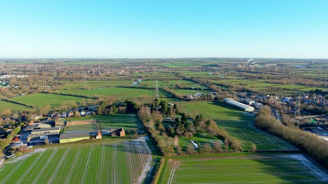 English countryside landscape surrounding small town expanding across green fields. Rural settlement developing infrastructure connecting villages farmland waterways. Aerial view exploring traditional