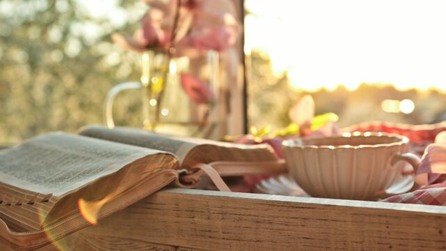 Cozy morning with an open book and a warm cup of tea by the window