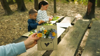 Children creating nature art with flowers and leaves outdoors at a picnic table © shine.graphics
