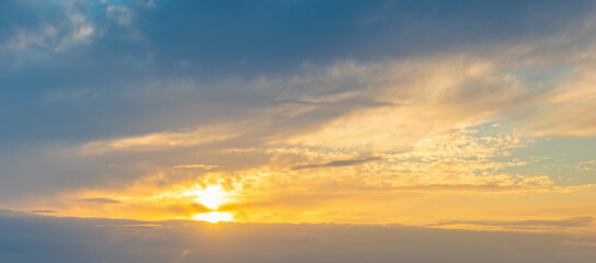 Sunset Sky with Sun among Blue and Yellow Clouds
