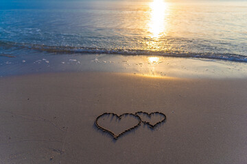 Two hearts drawn in the sand on the beach