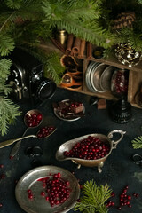 Berries, utensils, and decoration on a dark surface amid evergreen branches during a winter scene. Selective Focus © art_rich