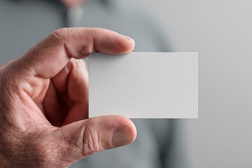 Obraz premium A hand holding a blank white business card mockup in front of a blurred background