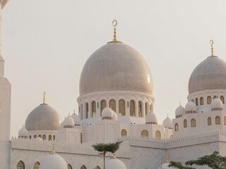 Fototapeta premium Grand white mosque with multiple domes and intricate architecture under a soft sky.