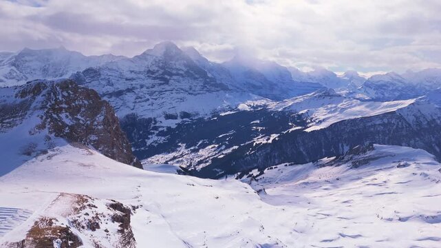 Eiger, Monch, Jungfrau Mountains on Sunny Winter Day. Bernese Alps. Switzerland. Aerial Drone Shot. Moving Forward and Downwards