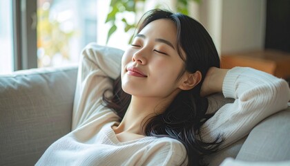 Serene woman relaxing on sofa with eyes closed, enjoying peaceful moment.