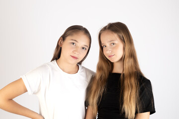 Two teenage girls hugging and smiling in studio