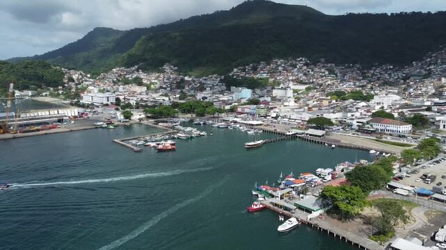 Angra Dos Reis, Brazil, January 13, 2025: Circling Drone shot of Angra dos Reis, the harbour area and the characteristic surrounding mountains with green rainforest behind the city and the harbour