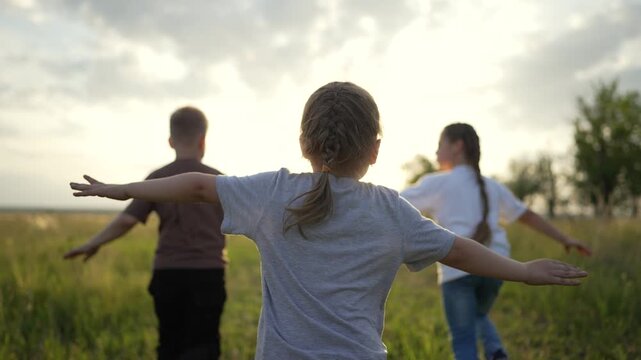 Children run through tall grass under warm sunset sun while child and kid play together in open field showing family bond and friend laughter in natural environment full of grass and nature joy