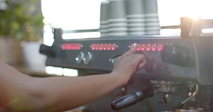Barista forearm is pressing oval control and tapping buttons on espresso machine to start brew