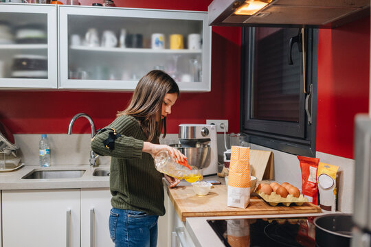 Girl learning baking skills in modern kitchen