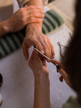Woman filing nails for man 