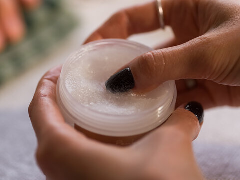 Woman taking skincare wax from jar