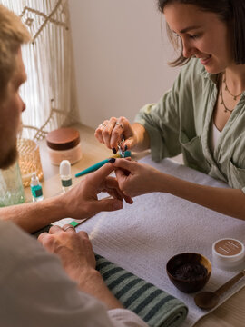 Focused woman removing cuticles to man 