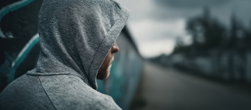Suspicious young man in hoodie, a stalker, view from behind