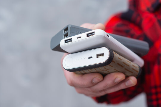 Close up of hand holding portable power banks with USB ports. Concept of mobile charging, backup energy, technology devices, travel power supply and modern gadgets.