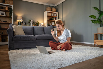 Obraz premium Young woman having video call waving hand on laptop