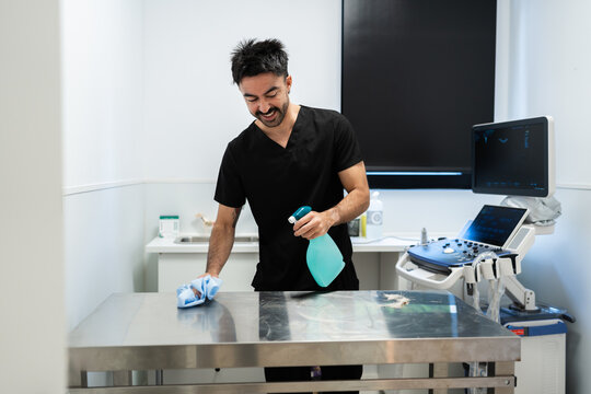 Male veterinarian cleaning examination table in hospital