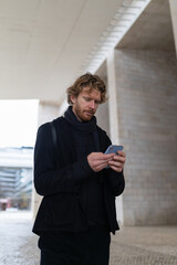 Fototapeta premium Young man using smartphone communicating online in urban setting