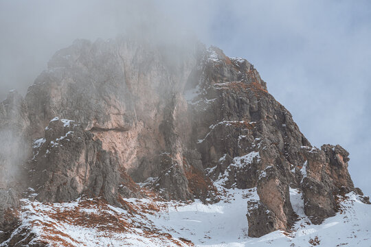 Dramatic winter view of Grignetta spires emerging from thick fog and low clouds. Moody alpine landscape with snow-covered rocky peaks in the Grigne mountains, Lecco, Italy - January 2026