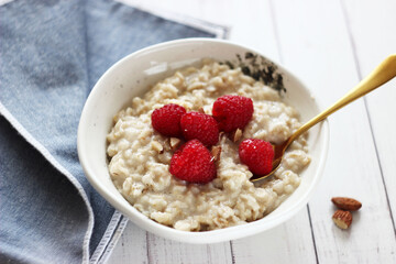 Oatmeal with raspberries in a plate on the table © Alena Bogdanova