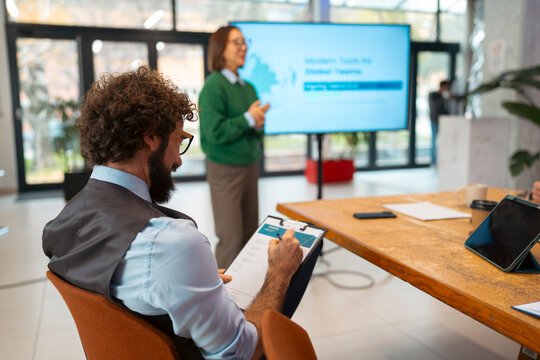 Businessman taking notes during a team presentation in a modern office