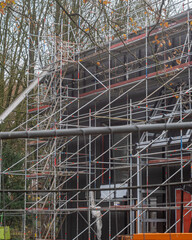 Construction work is ongoing with scaffolding around a building in a city during autumn days
