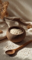 Close-up of rice in a wooden bowl with spoon and dried florals on beige fabric