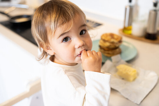 Child eating snack in kitchen during daytime meal