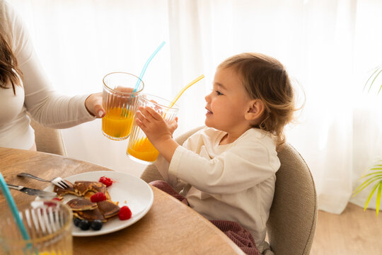 Child enjoys breakfast with juice and pancakes at home