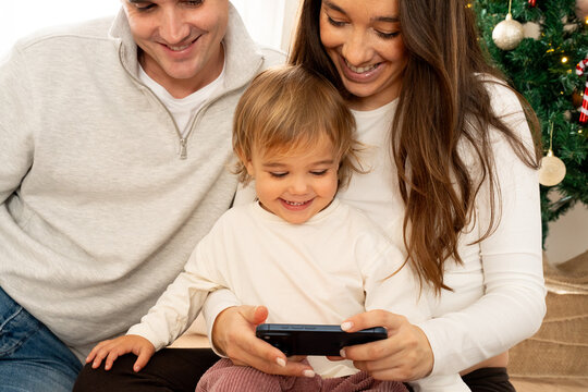 Family enjoys time together while looking at a smartphone indoors